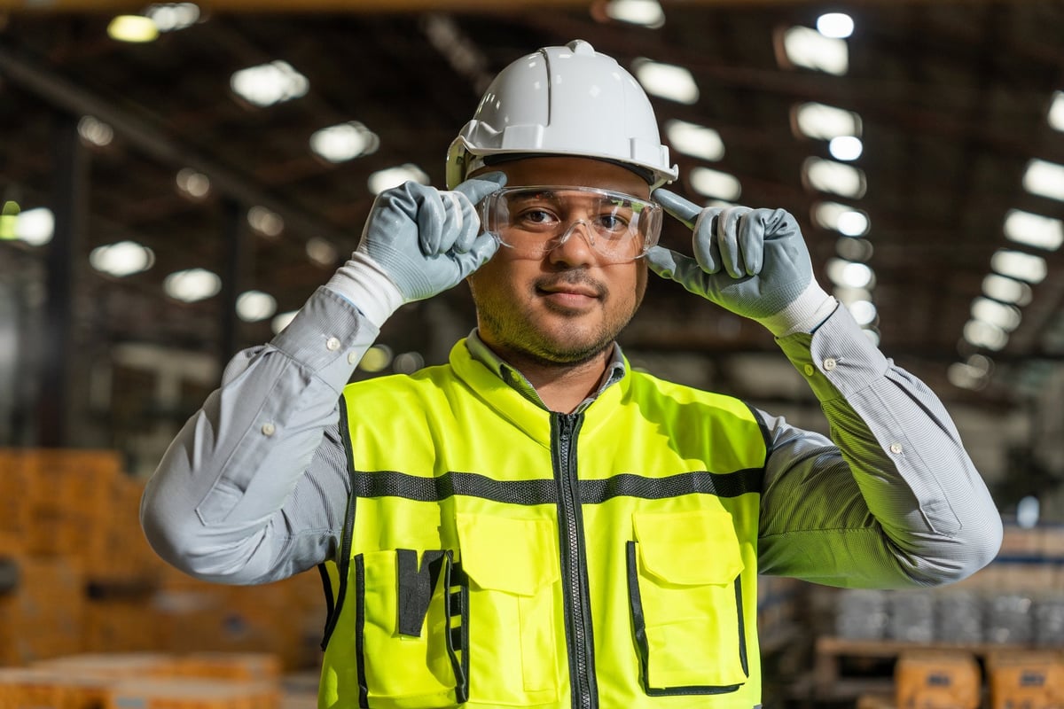 Worker wearing and adjusting protective safety glasses in a professional environment